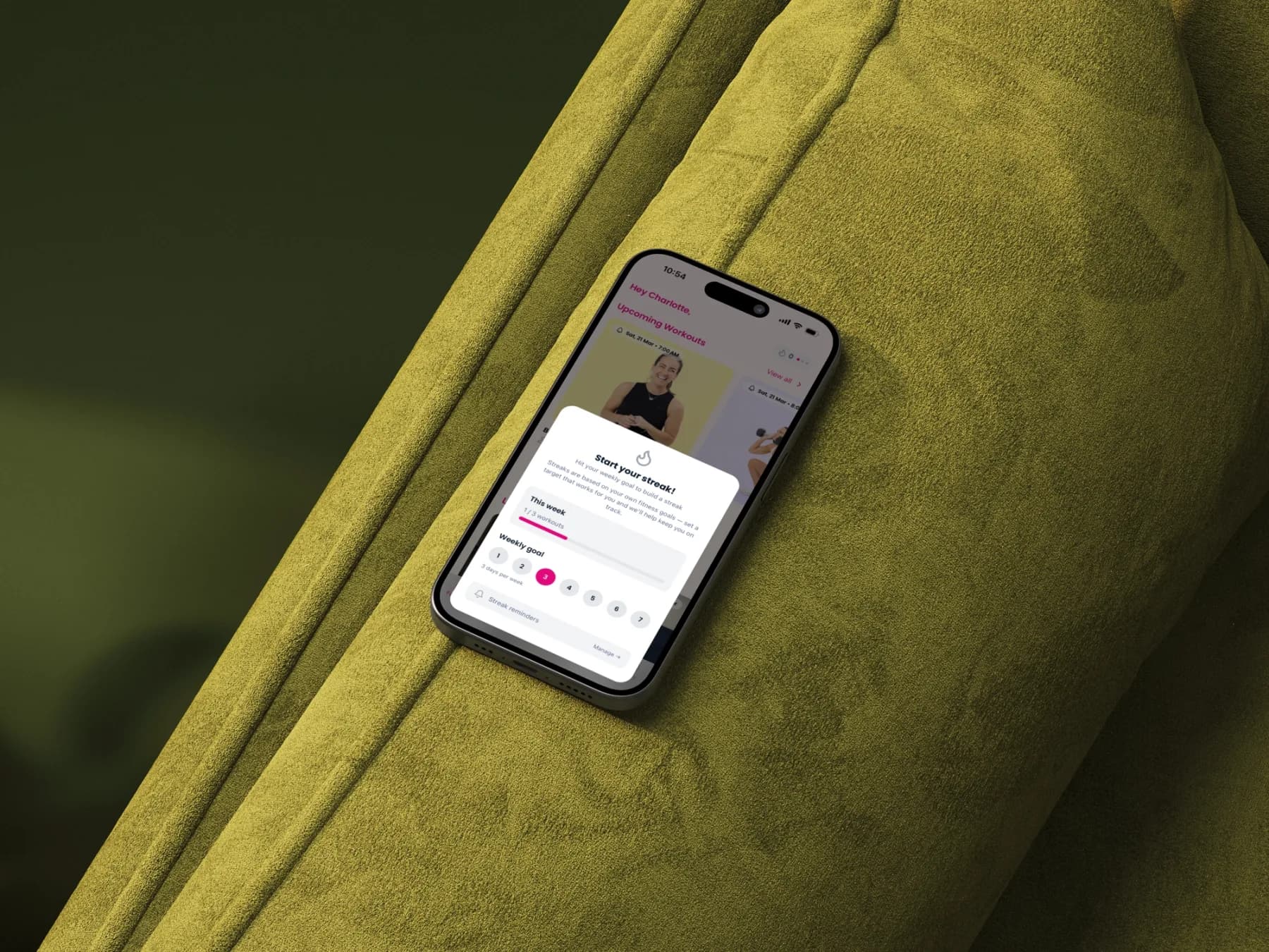 The Move it Mama app on a phone resting on an olive green velvet couch
