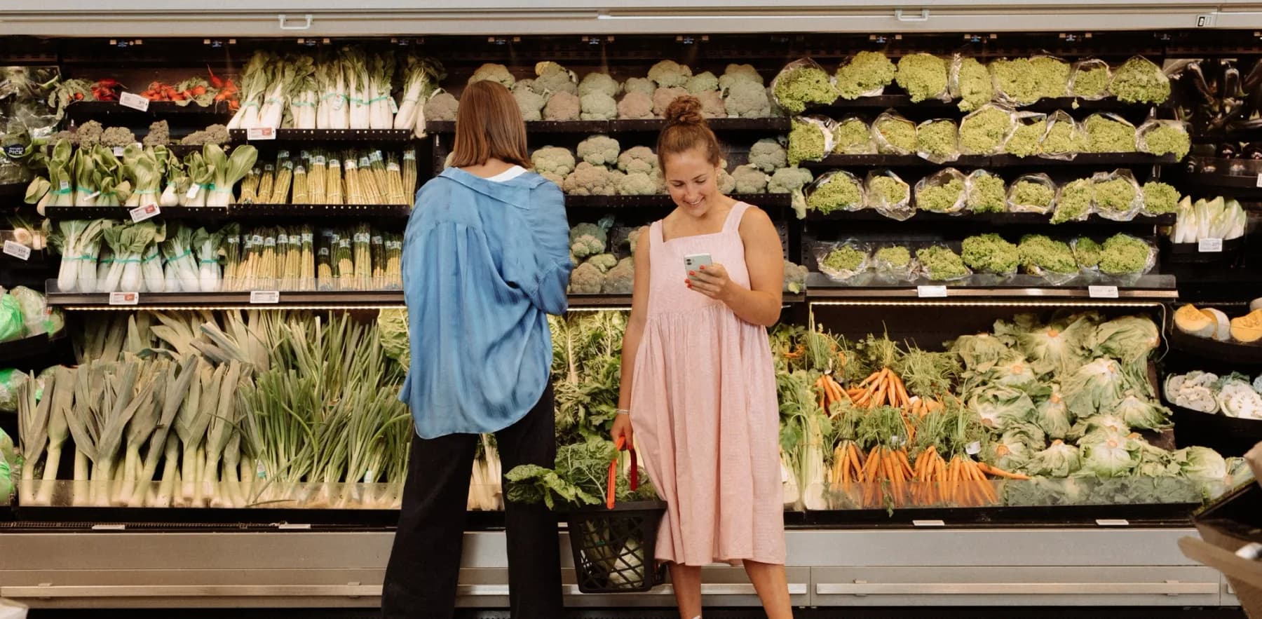 The Two Raw Sisters shopping for vegetables in a supermarket produce aisle