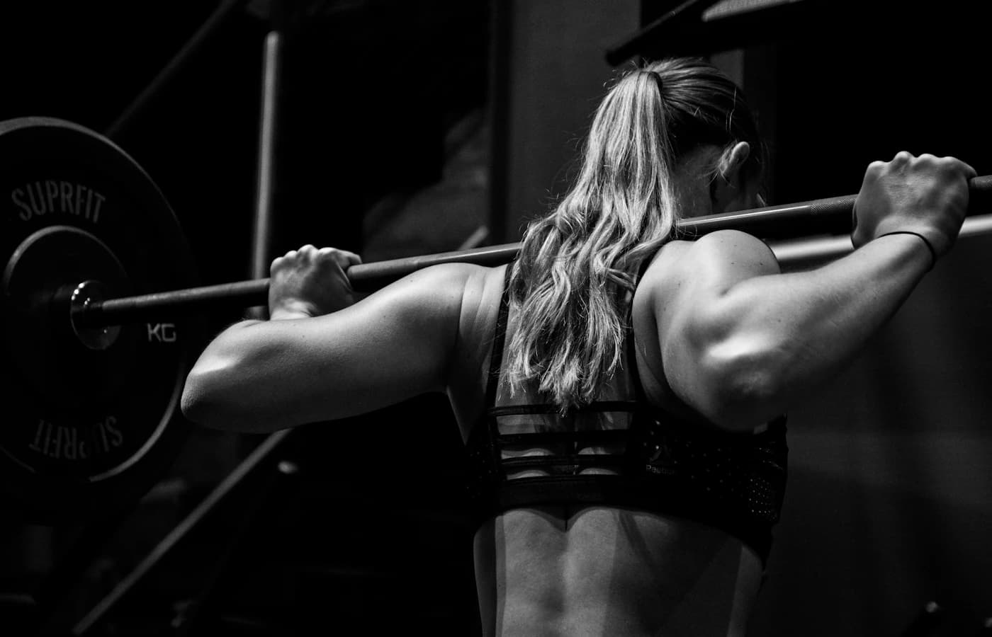 A woman mid-squat with a barbell across her shoulders